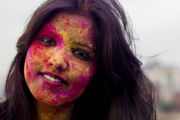 Portré egy gyönyörű lányról, tele színes porral az egész testen. A fiatal lány színekkel játszik Holi alkalmából. Az indiai fesztivál koncepciója Holi. Az írásos szöveghez rendelkezésre álló üres hely. - Fotó, kép