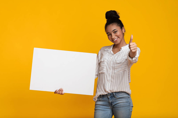 Amigável menina negra segurando em branco Placard e mostrando polegar para cima
 - Foto, Imagem