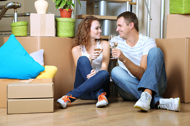 Young couple celebrating moving to new home sitting among boxes - Photo, image