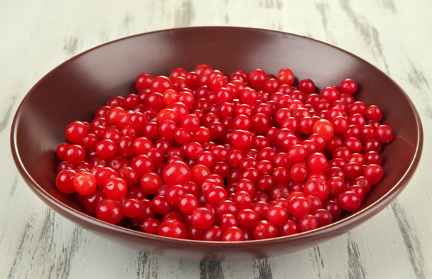 Red berries of viburnum in bowl on wooden background - Фото, зображення