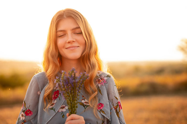 Happy young woman with flowers in field - Foto, Imagen