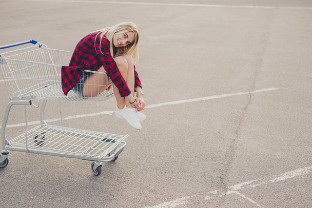 Positive young woman in shopping cart - Zdjęcie, obraz