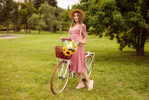 Elegant female with vintage bike standing on park lawn - Foto, Imagem