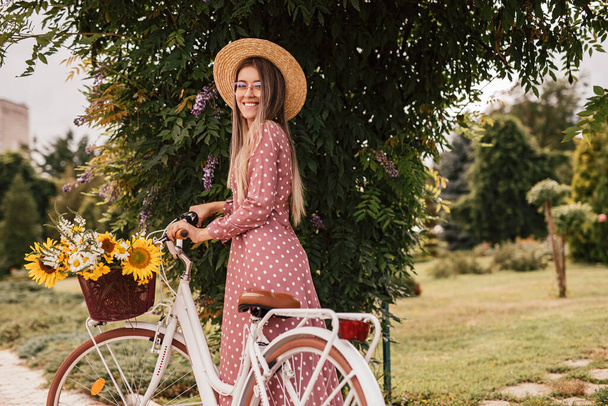 Femme heureuse avec vélo près de l'arbre en fleurs dans le parc
 - Photo, image