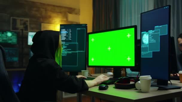 Hacker girl wearing a black hoodie in front of computer - Materiał filmowy, wideo