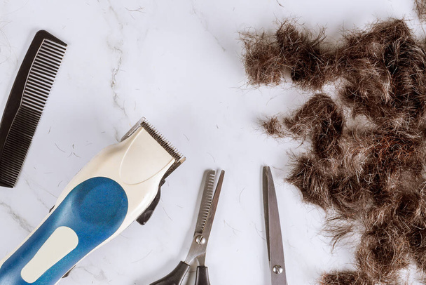 Pile de cheveux coupés et tondeuses électriques de cheveux quelques tondeuses sur un ciseau avec des cheveux de peigne
 - Photo, image