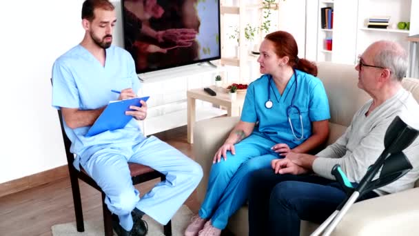 Two doctors talking with old man in nursing home - Video, Çekim