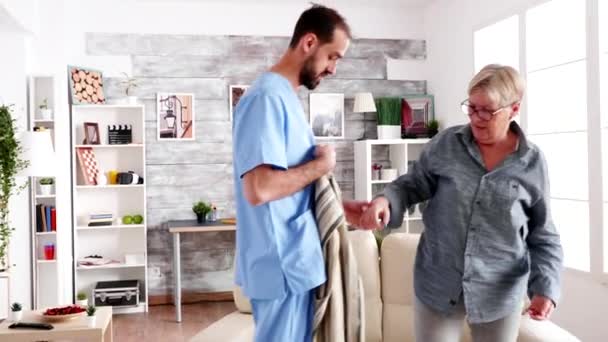 Male nurse helping senior woman getting dressed - Video