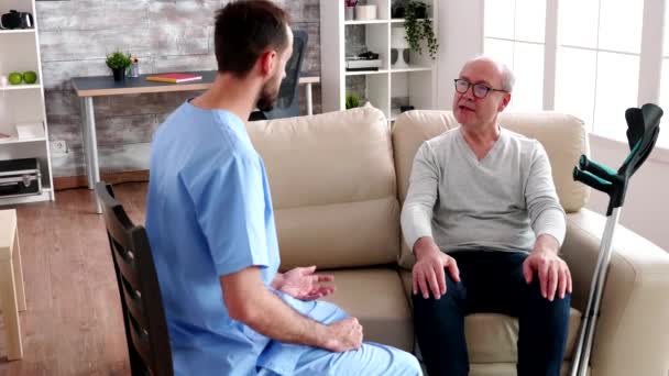 Jovem médico barbudo conversando com homem idoso
 - Filmagem, Vídeo