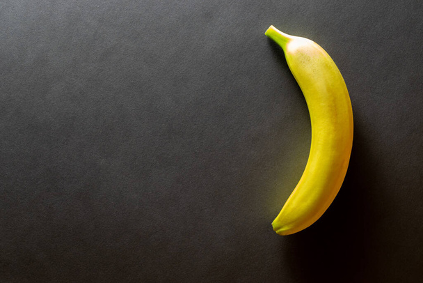 Yellow background design. Bananas isolated on black with copy space. View from above. - Фото, зображення
