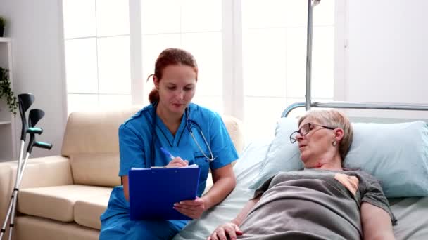 Nainen sairaanhoitaja tekee muistiinpanoja leikepöydälle hoitokodissa
 - Materiaali, video