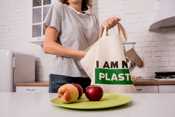 Young girl holding a cloth bag. At the kitchen. I am not plastic.  - Foto, Imagen