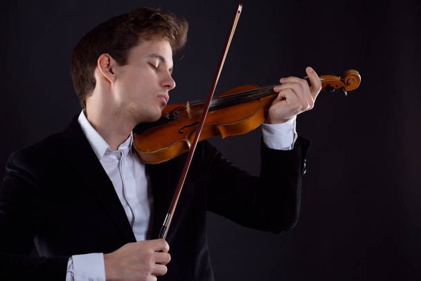 The violinist closes his eyes from overflowing feelings and plays the instrument - Photo, Image