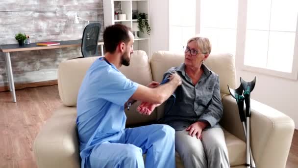 Doctor in retirement home measuring the blood pressure - Filmagem, Vídeo