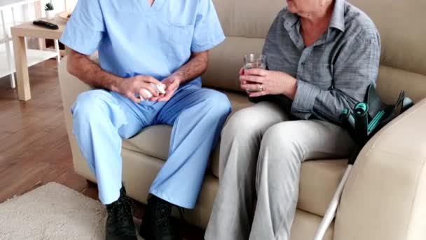 Infermiera di sesso maschile sul divano con anziana donna in pensione che dà le sue cure mediche in casa di riposo
 - Filmati, video