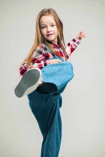 little girl makes a kick. fashionable children's studio shooting - Fotó, kép