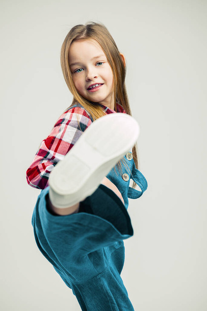 little girl makes a kick. fashionable children's studio shooting - Φωτογραφία, εικόνα