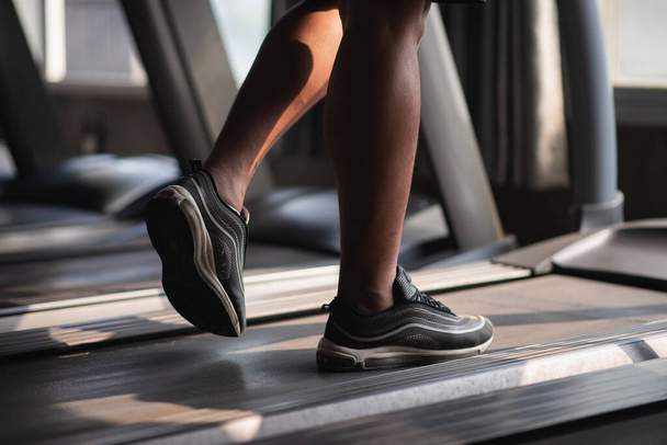 κοντινό πλάνο των ποδιών του αθλητισμού άνθρωπος χρησιμοποιώντας διάδρομο στο γυμναστήριο - Φωτογραφία, εικόνα
