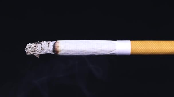 Kouřící cigareta na černém pozadí. Kouř z cigarety. Zpomal. Koncept zdravého životního stylu. - Záběry, video