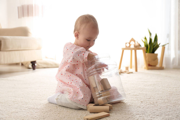 Cute child playing with wooden building blocks on floor at home - Valokuva, kuva