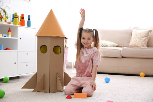 Cute little child playing with cardboard rocket at home - Foto, immagini