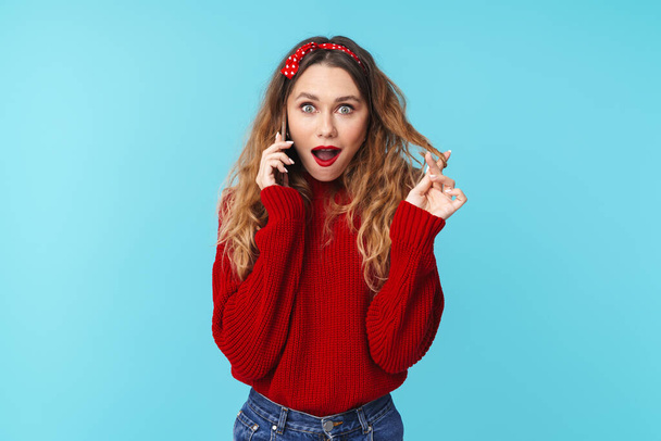 Image of young nice woman talking on smartphone and expressing surprise isolated over blue background - Fotografie, Obrázek