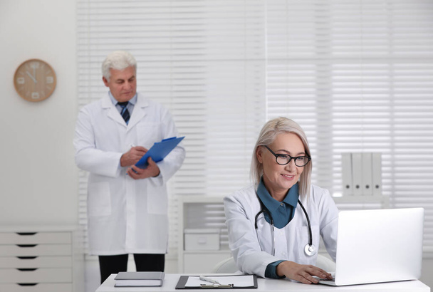 Érett nő orvos dolgozik laptop asztalnál az irodában - Fotó, kép