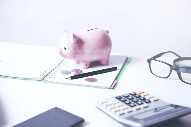 piggy bank and calculator on notepad on desk - Foto, Bild