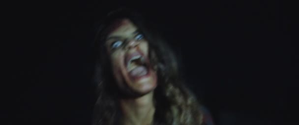 Zombie žena s bílýma očima křičí, vypadá děsivě a děsivě. Žena se mění v zombie koncept. Snímek ve stylu hororu. Zblízka, ruční, filmový pohled. BMPCC 4K - Záběry, video