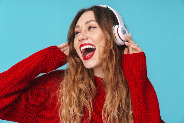 Image of cheerful pretty woman using headphones and smiling isolated over blue background - Fotografie, Obrázek