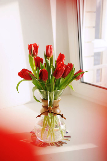 Bouquet of red spring tulips in a glass coffee decanter on tasters flavor wheel. White background, sunlight - Foto, afbeelding
