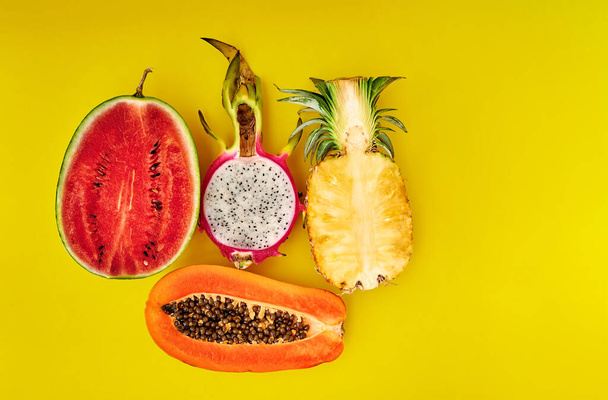 Half tropical fruits of pineapple, papaya, watermelon, dragon on a yellow background. Minimal style. Space for text - Fotoğraf, Görsel