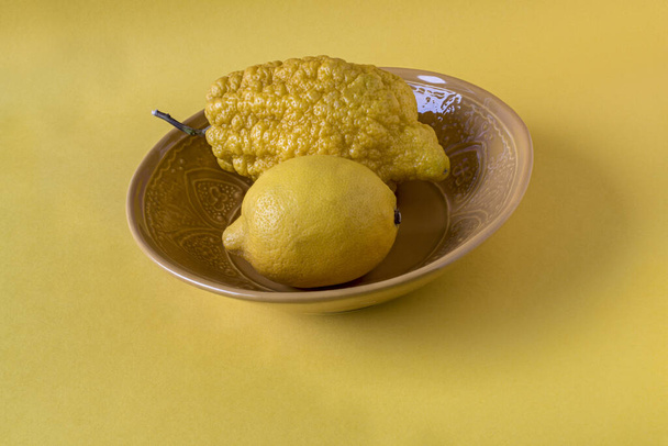 Лимон і цитрон у мисці на жовтому тлі
 - Фото, зображення