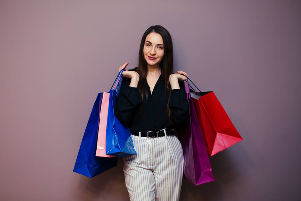beautiful young woman with colored shopping bags on purple background. - Foto, imagen