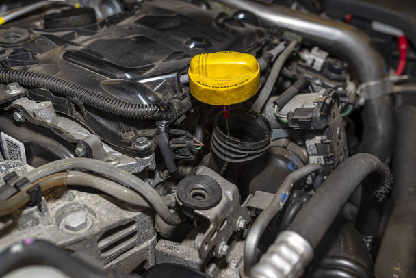 Compartimento del motor en el coche usado relleno de aceite abierto visible en amarillo y partes del motor
. - Foto, Imagen