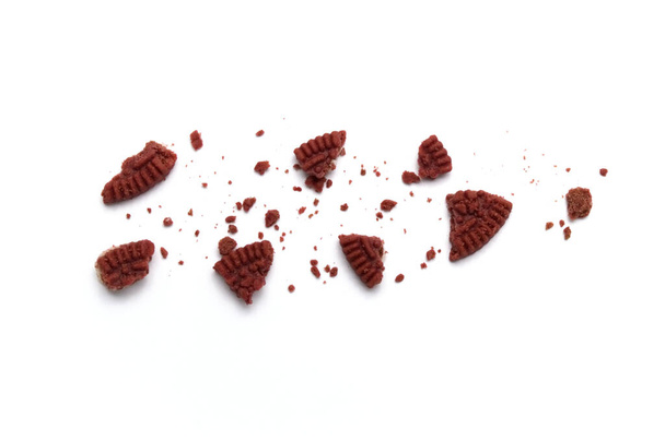 Crumbs of Red velvet sandwich cookies  filled with cheesecake flavored cream on white background.   - Foto, imagen