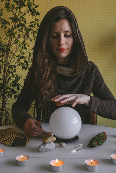 young mysterious woman holds her hands over a crystal ball of predictions - Φωτογραφία, εικόνα