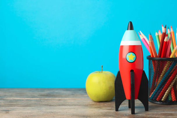 Bright toy rocket and school supplies on wooden desk. Space for text - Valokuva, kuva