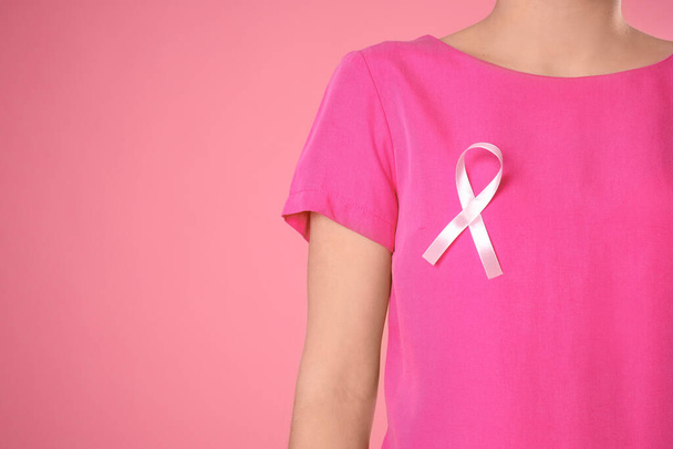 Крупный план женщины с розовой лентой на цветном фоне, место для текста. Осознание рака молочной железы
 - Фото, изображение