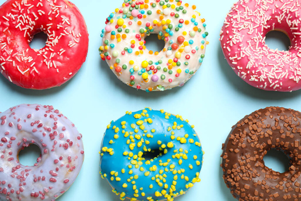 Delicious glazed donuts on light blue background, flat lay - Фото, зображення
