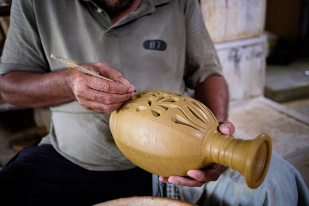 Primer plano de artesano local demuestra en la fabricación de tarro de arcilla tradicional llamado Labu Sayong o Essence Jar de Sayong en Kuala Kangsar, Perak, Malasia. Concepto de cerámica
. - Foto, Imagen