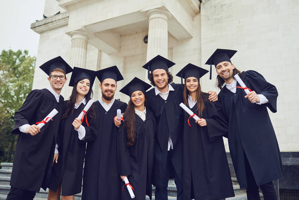 A group of graduates with scrolls in their hands are smiling - Foto, imagen