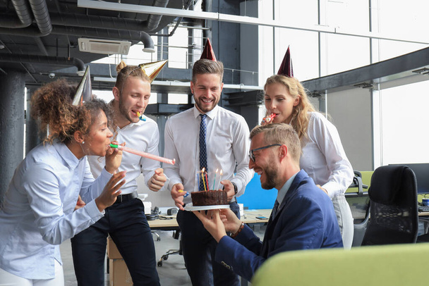 Glückliche Geschäftsleute mit Geburtstagstorte begrüßen Kollegen auf Büroparty - Foto, Bild