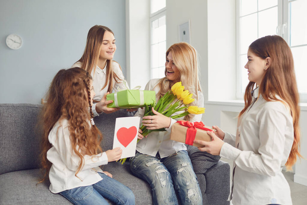 Happy Mothers Day. Children daughters give mom a bouquet of flowers at home. - Foto, imagen