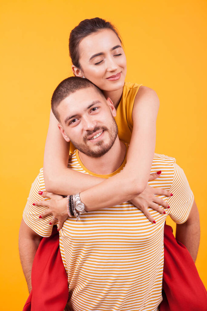 Beautiful girlfriend with eyes closed while boyfriend ofer a piggyback - Фото, зображення