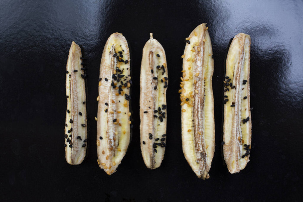 4 Plátano cultivado al horno con semillas de sésamo negro, Sesamum indicum en bandeja de acero inoxidable negro, Close up & Macro shot, concepto de comida saludable
 - Foto, imagen