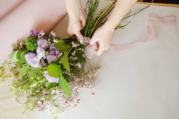 femme fleuriste faire bouquet de fleurs violettes à l'intérieur. Fleuriste féminine préparant le bouquet à la boutique de fleurs. entrepreneuriat, petite entreprise, concept de lieu de travail. Espace de copie
 - Photo, image