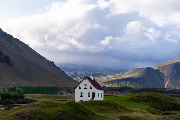 Farmhouse on hill in Iceland with cloudy sky and nice view on background  - Fotó, kép