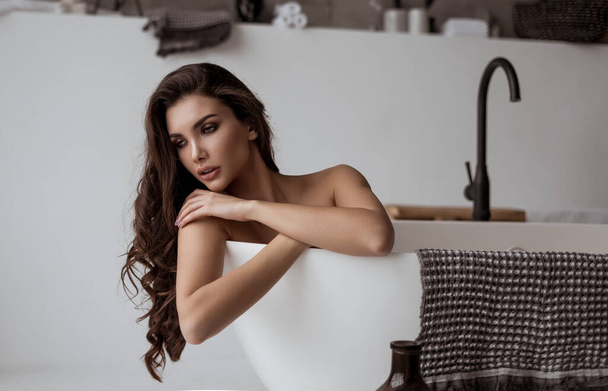 Luxury bath woman relaxing in hotel spa bathtub or home bathroom for total relaxation. young lady taking a bath in warm water, winter wellness. brunette with long healthy hair. - 写真・画像
