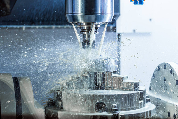 Vertical photo of industrial wet milling process in 5-axis cnc machine with coolant flow under pressure and freezed splashes. - Photo, Image